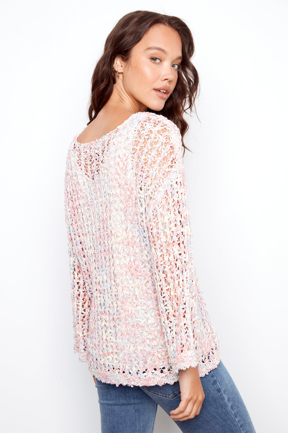 Woman wearing a light pink crochet top against a white background