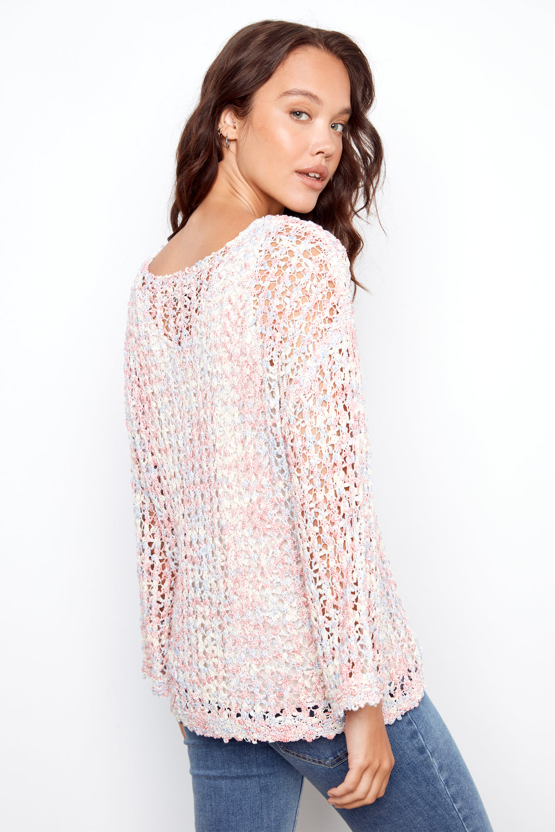 Woman wearing a light pink crochet top against a white background