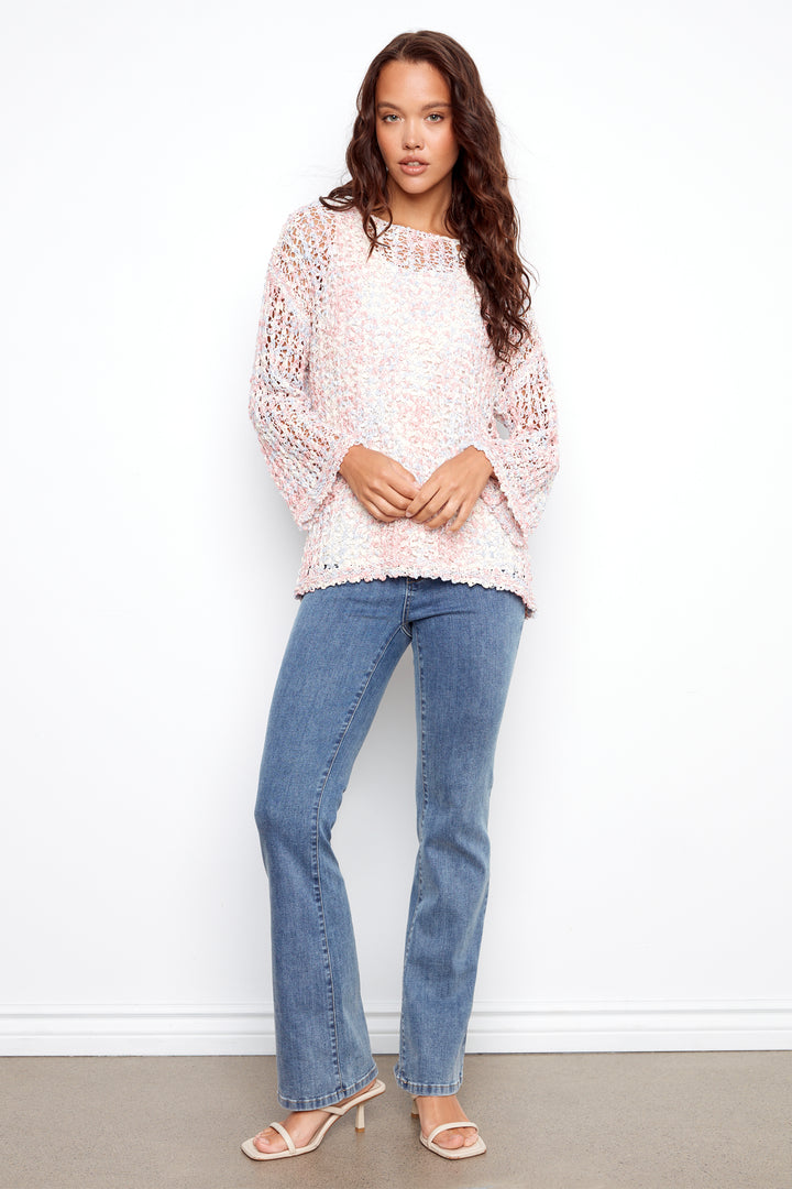 Woman wearing a light pink lace top and blue jeans against a white background