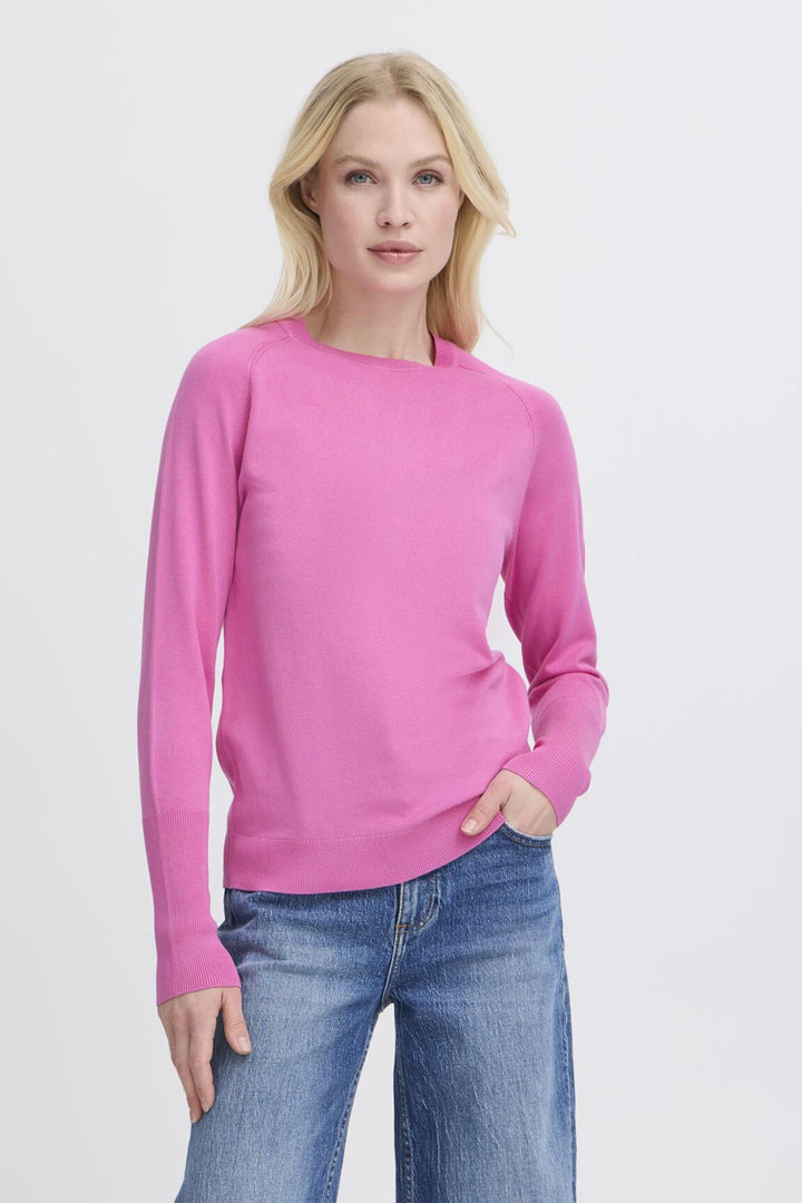 Woman wearing a pink sweater and blue jeans on a white background