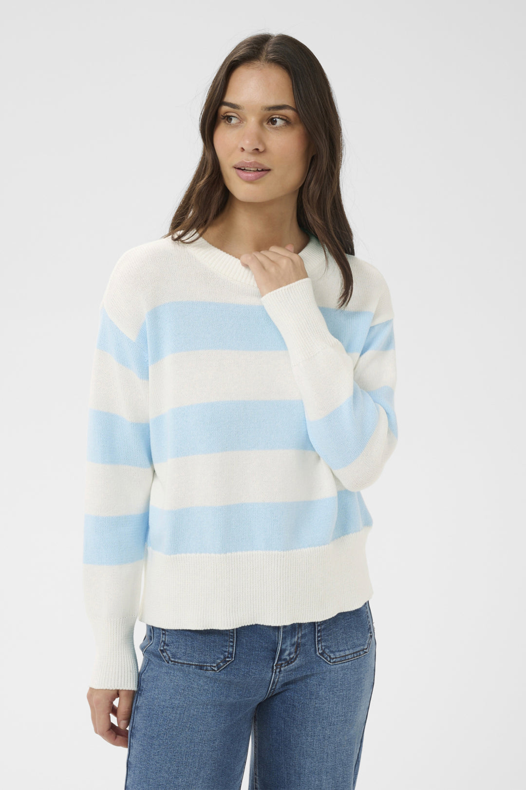 Woman wearing a striped sweater and jeans on a plain background