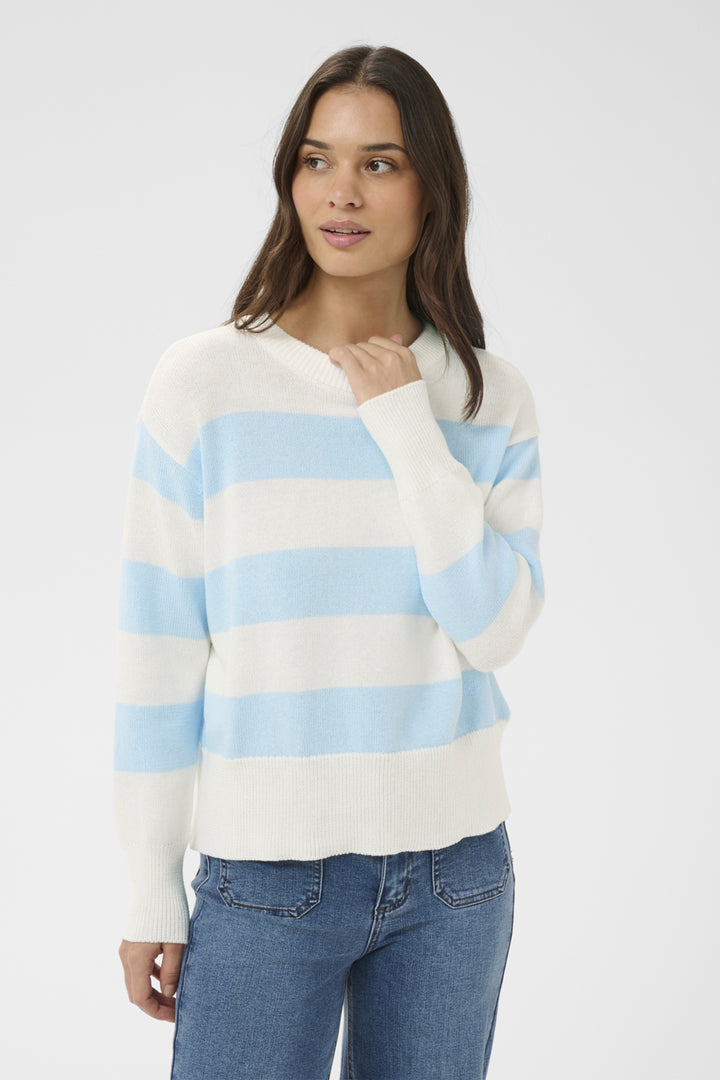 Woman wearing a striped sweater and jeans on a plain background