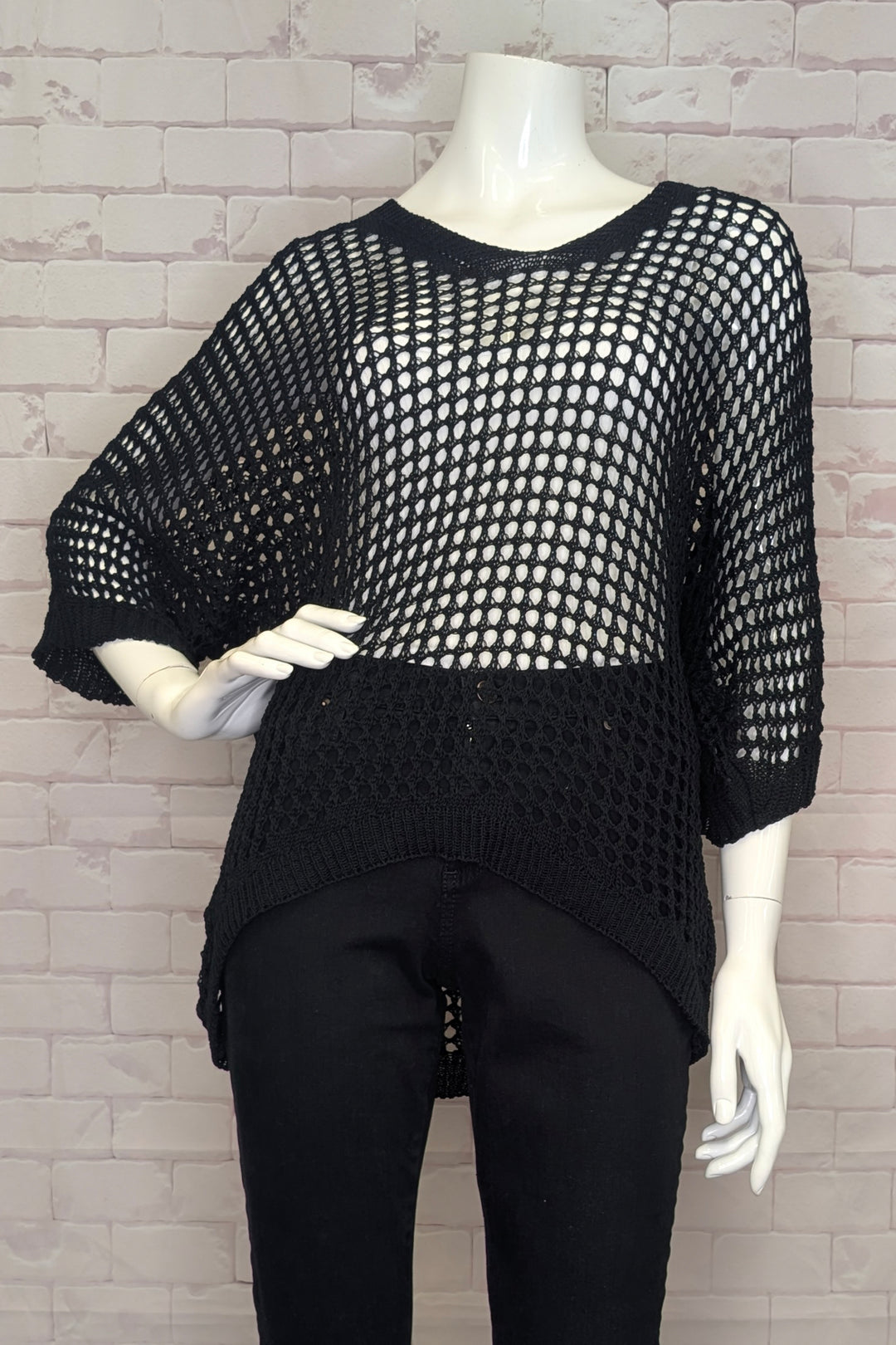 Black mesh top on a mannequin against a brick wall background