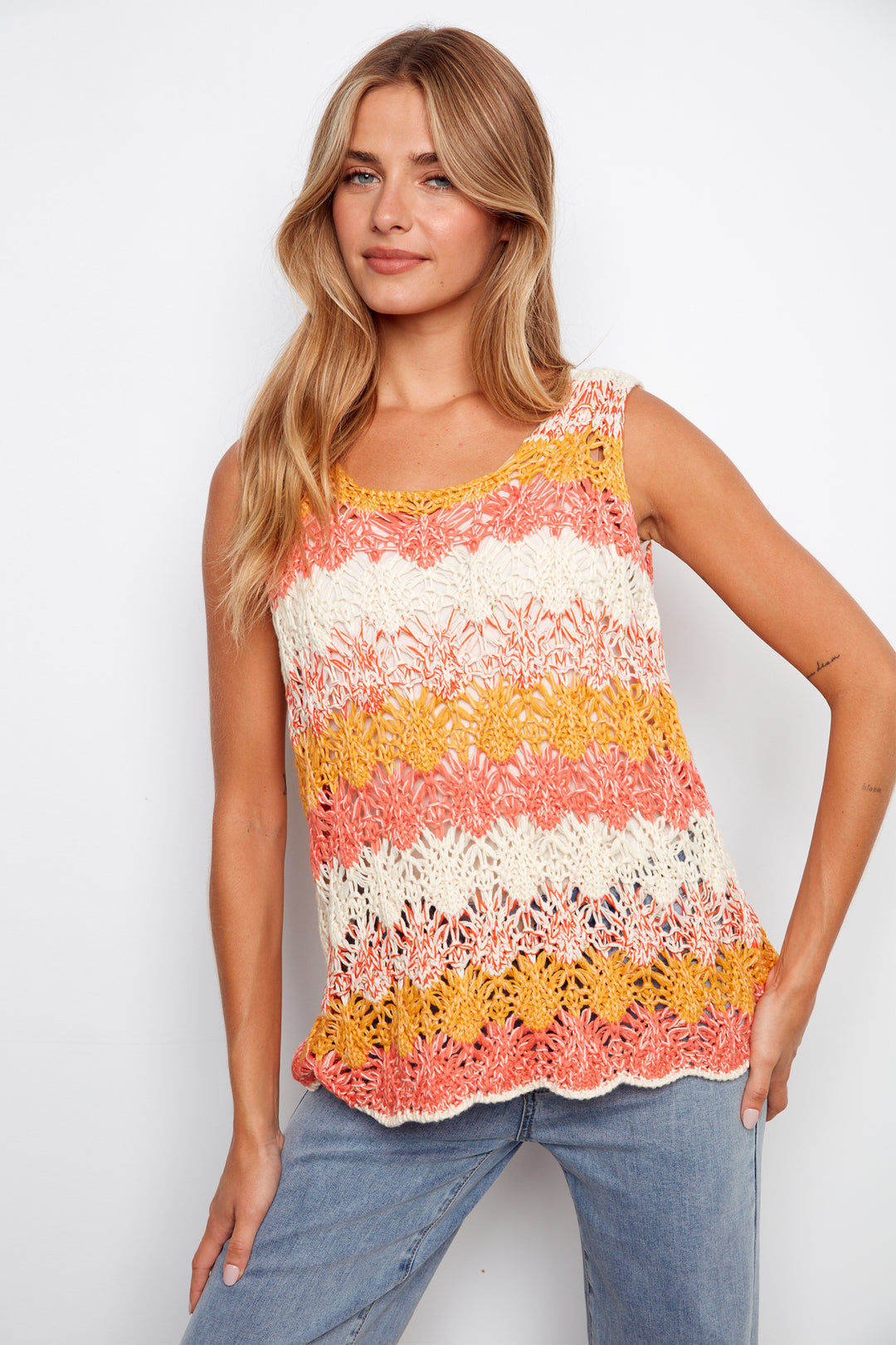 Woman wearing a colorful striped crochet tank top against a white background