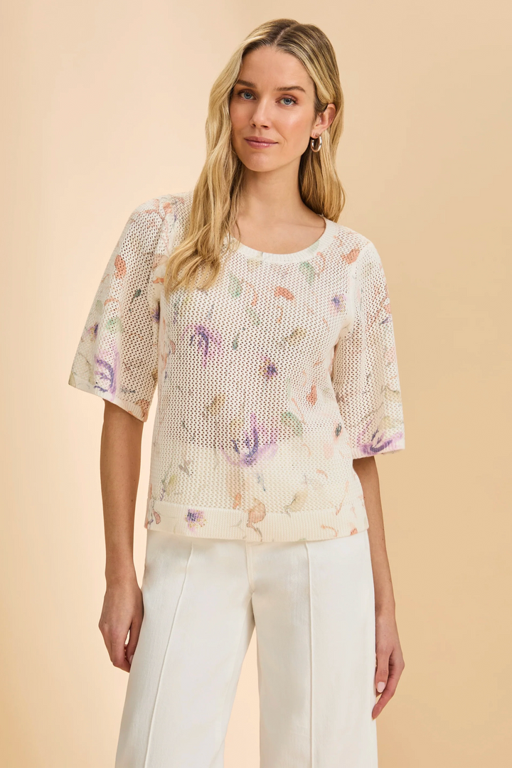 Woman wearing a floral patterned top against a beige background