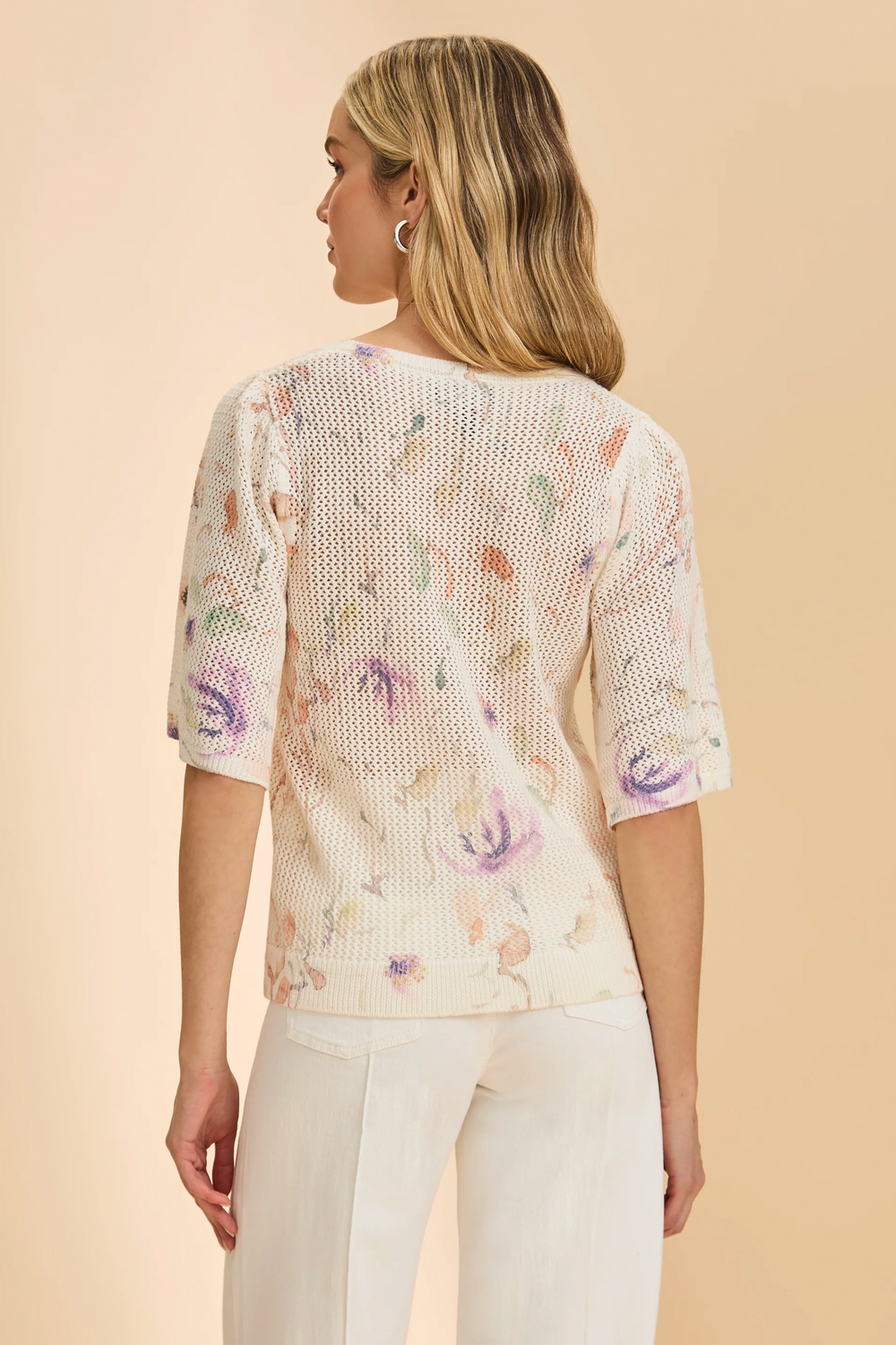 Woman wearing a floral patterned top against a beige background