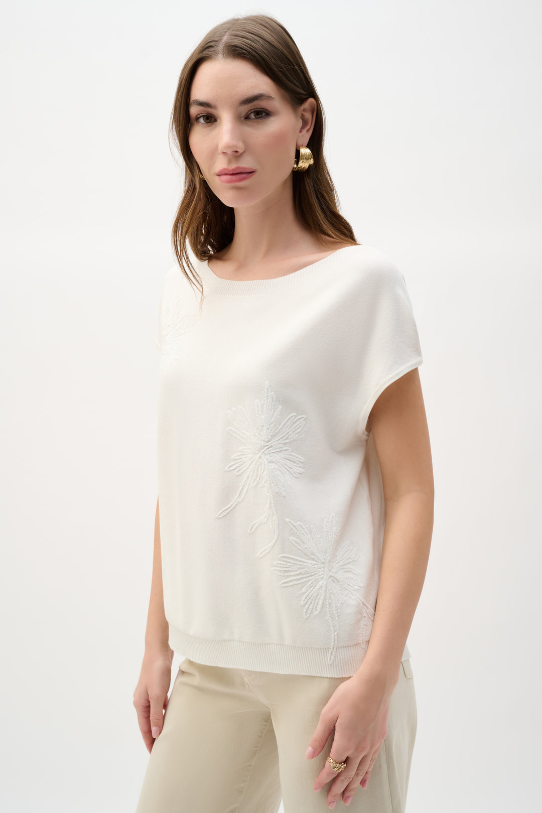 Woman wearing a white blouse with a subtle pattern on a plain background