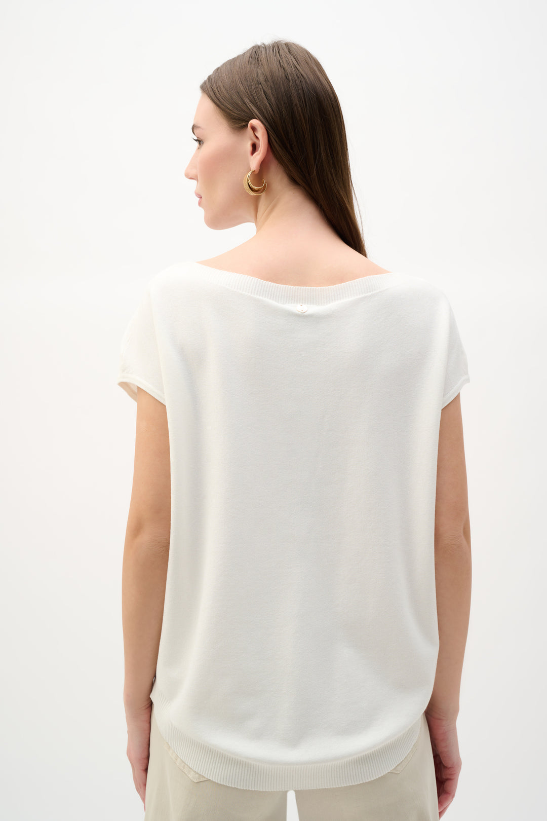Woman wearing a white sleeveless top against a plain background
