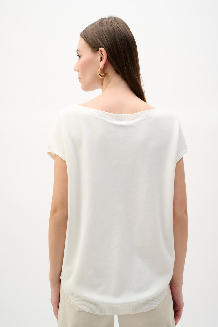 Woman wearing a white sleeveless top against a plain background