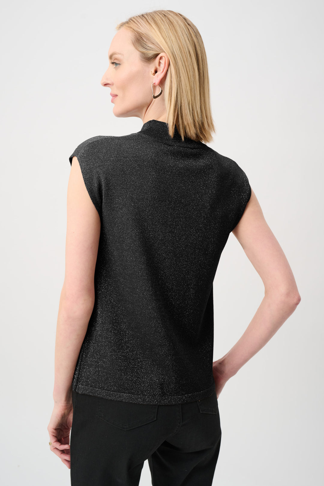Woman wearing a black sleeveless top against a white background