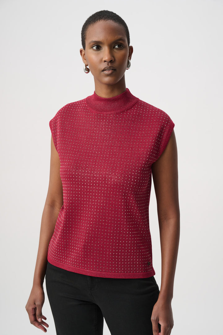 Woman wearing a red sleeveless top with rhinestones and black pants on a white background