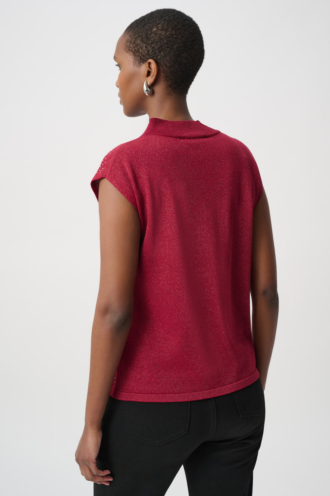 Woman shown from the back wearing a red sleeveless top with rhinestones and black pants on a white background