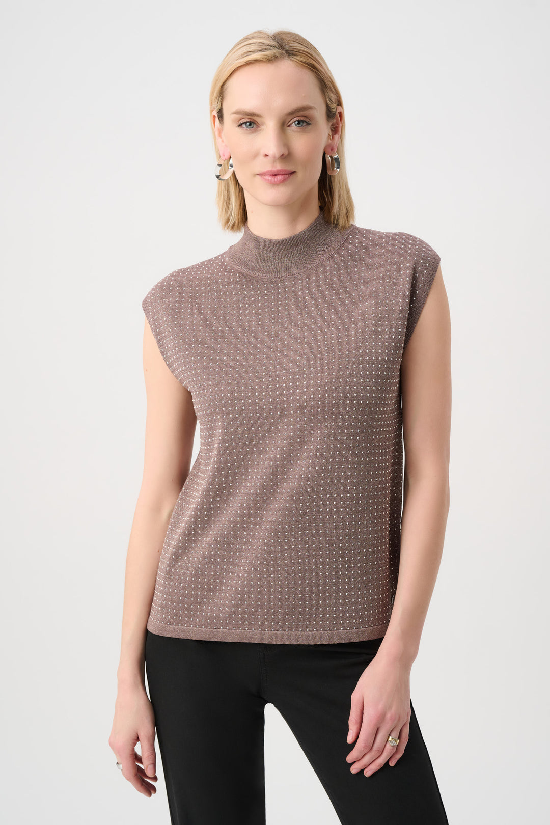 Woman wearing a sleeveless patterned top against a white background