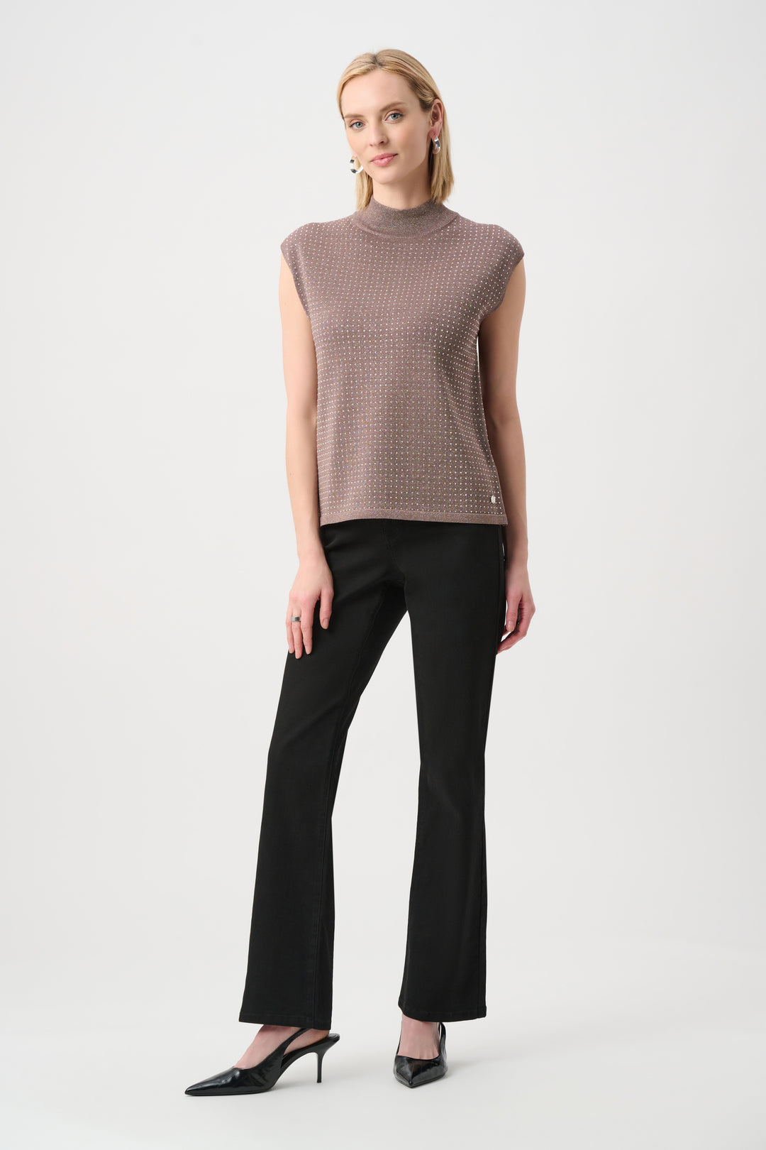 Woman wearing a sleeveless patterned top and black pants on a white background
