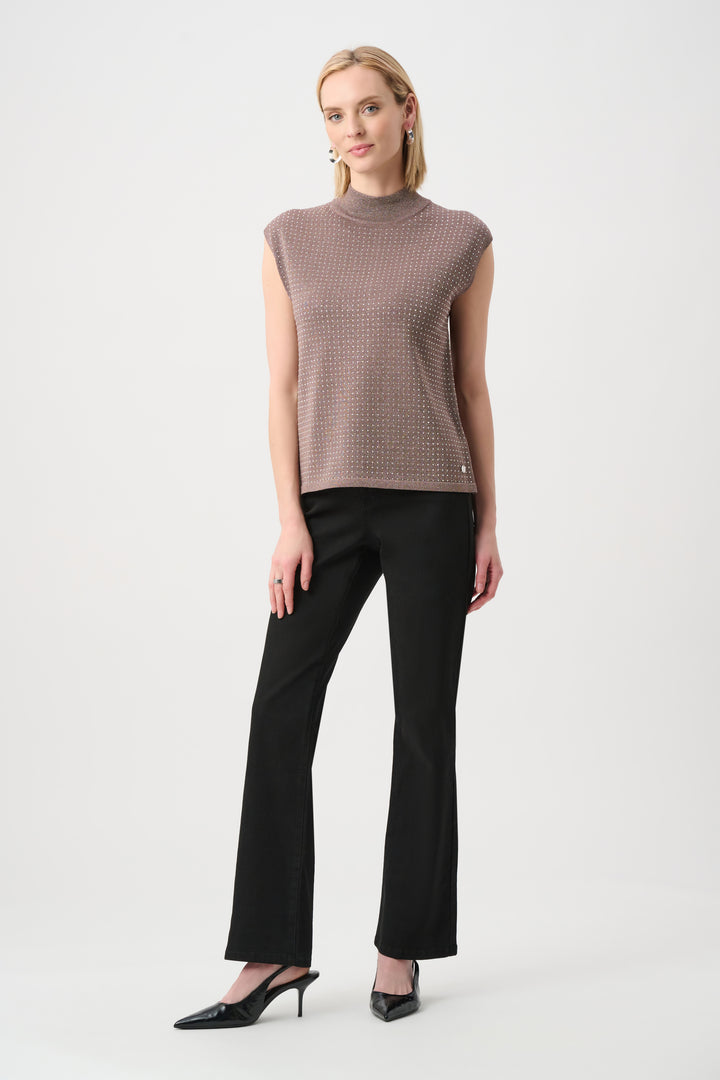 Woman wearing a sleeveless patterned top and black pants on a white background