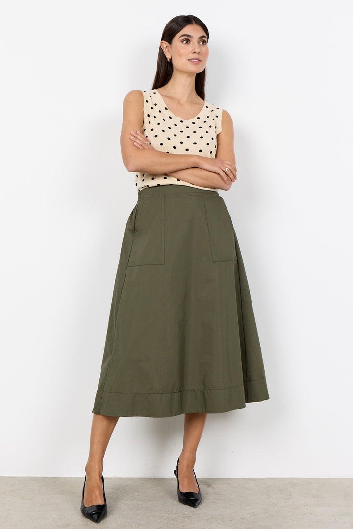 woman wearing a cream polka dot vest top and a khaki skirt on a white background.