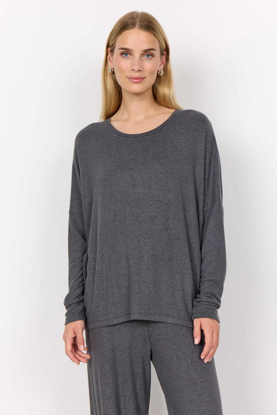 woman wearing an oversized long sleeve sweater with matching pants on a white background. 