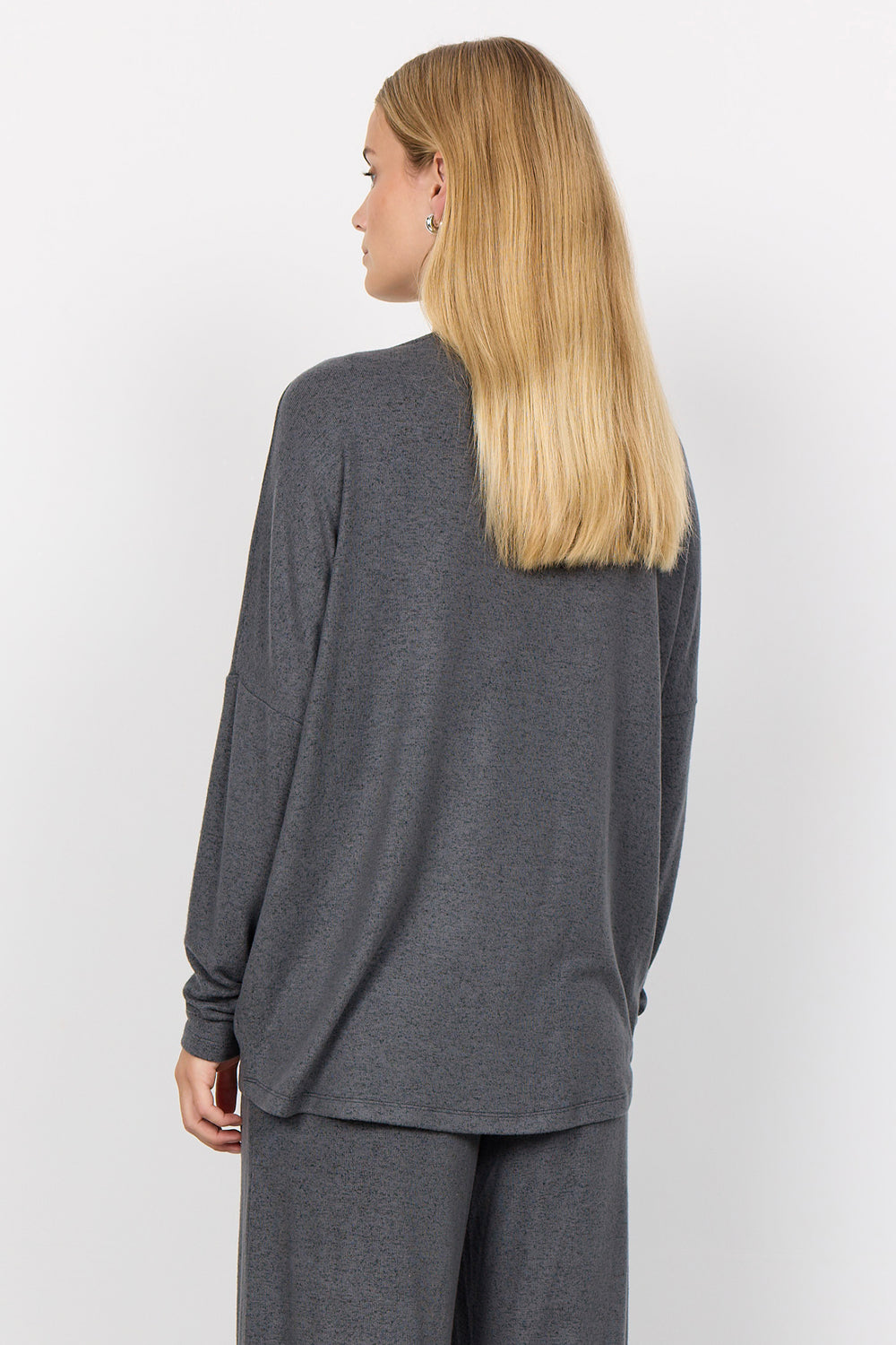 woman wearing an oversized long sleeve sweater with matching pants on a white background. 