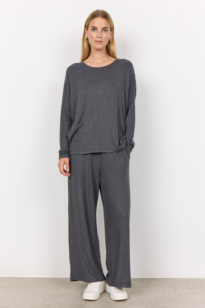 woman wearing an oversized long sleeve sweater with matching pants on a white background. 