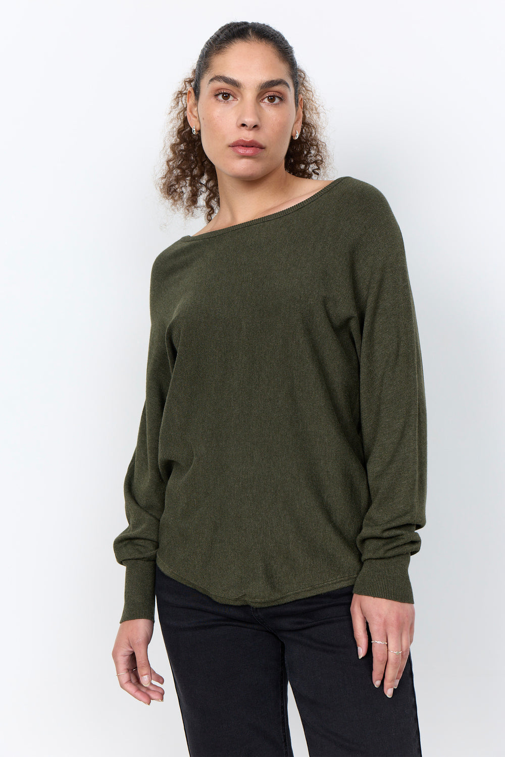 woman wearing a loose long sleeve sweater on a white background. 