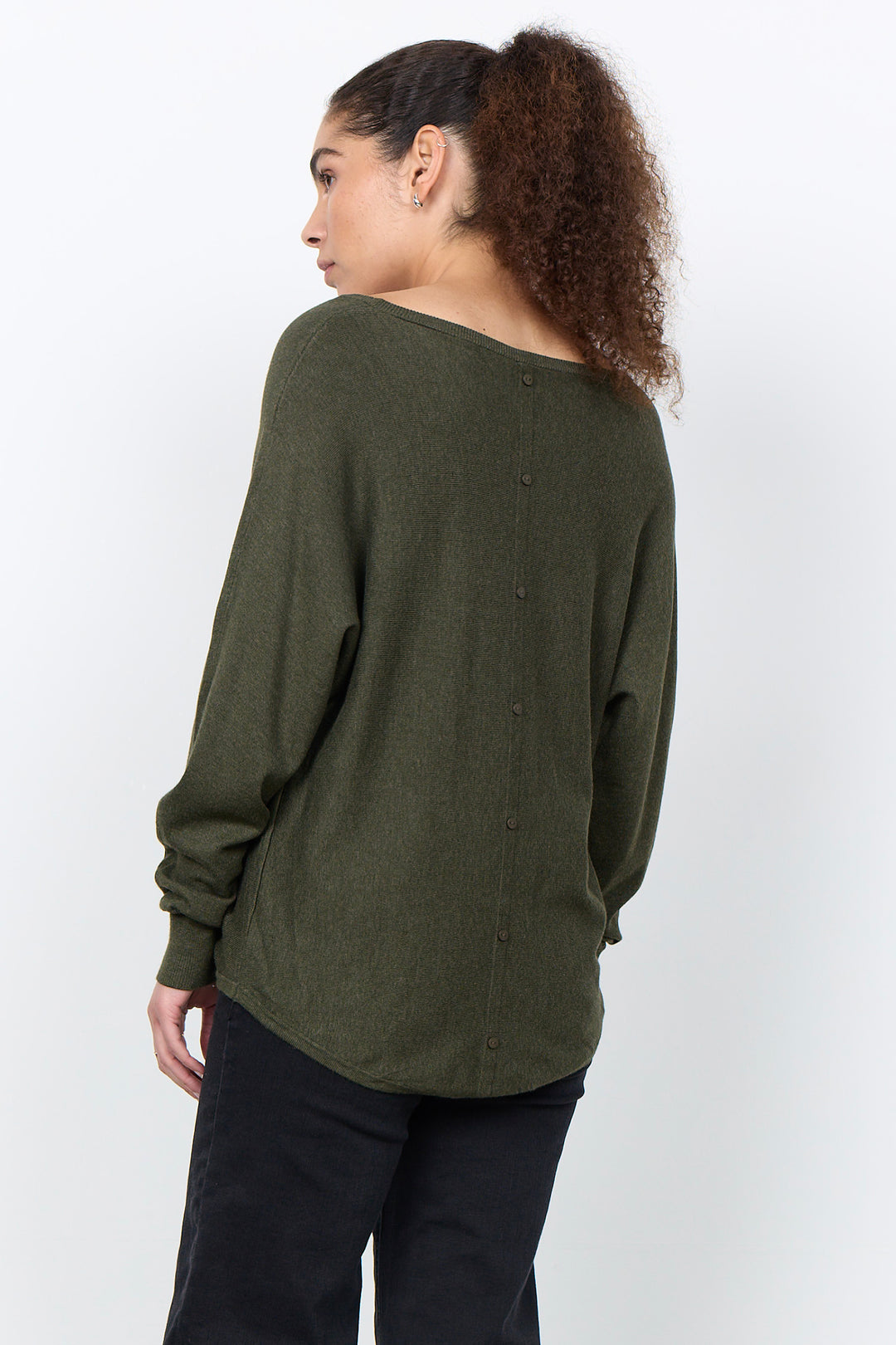 woman wearing a loose long sleeve sweater on a white background. 
