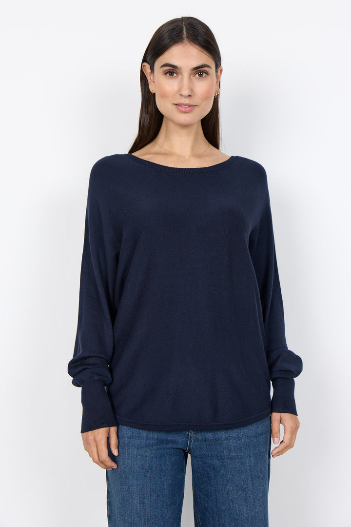 woman wearing a loose long sleeve sweater on a white background. 