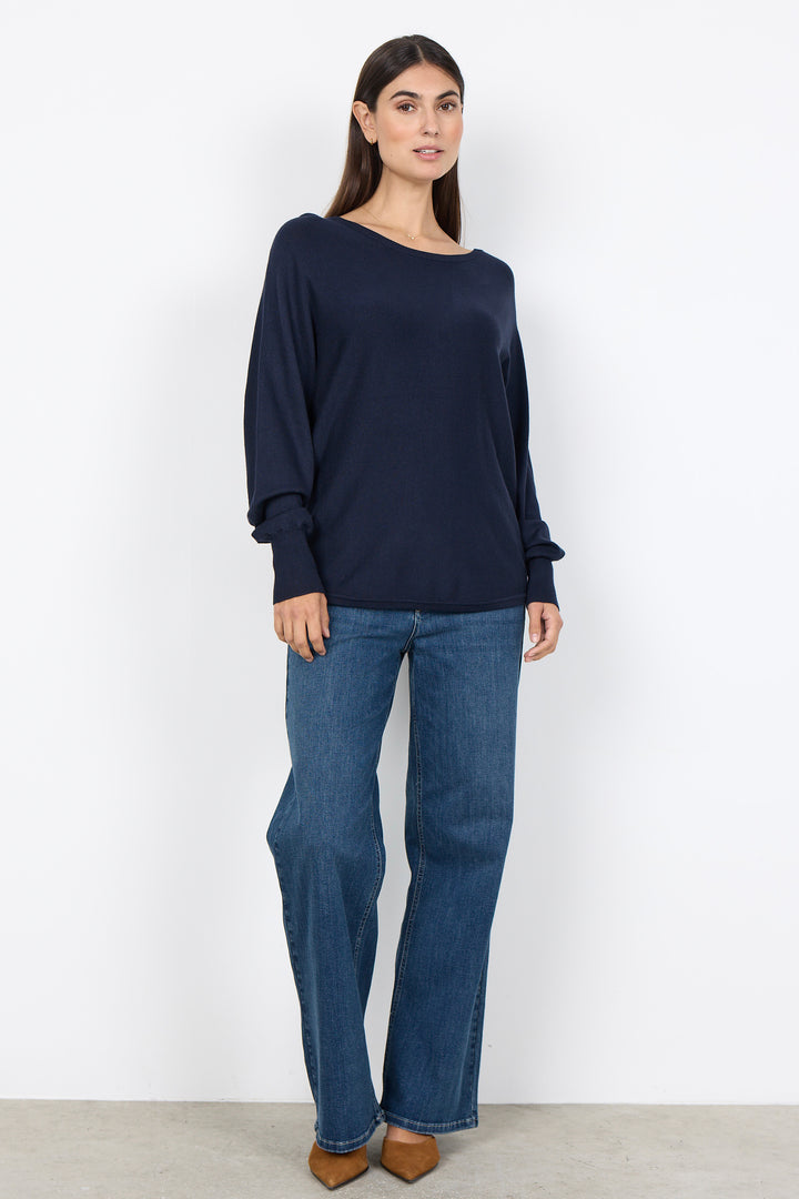 woman wearing a loose long sleeve sweater on a white background. 