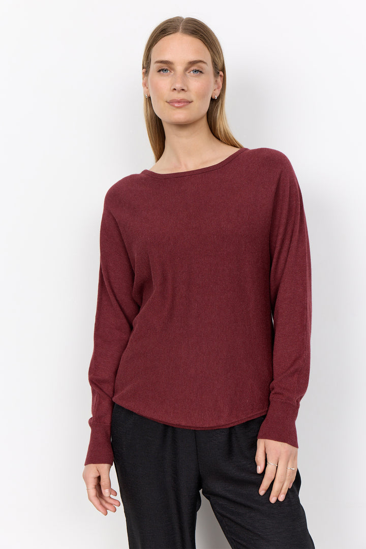 woman wearing a loose long sleeve sweater on a white background. 