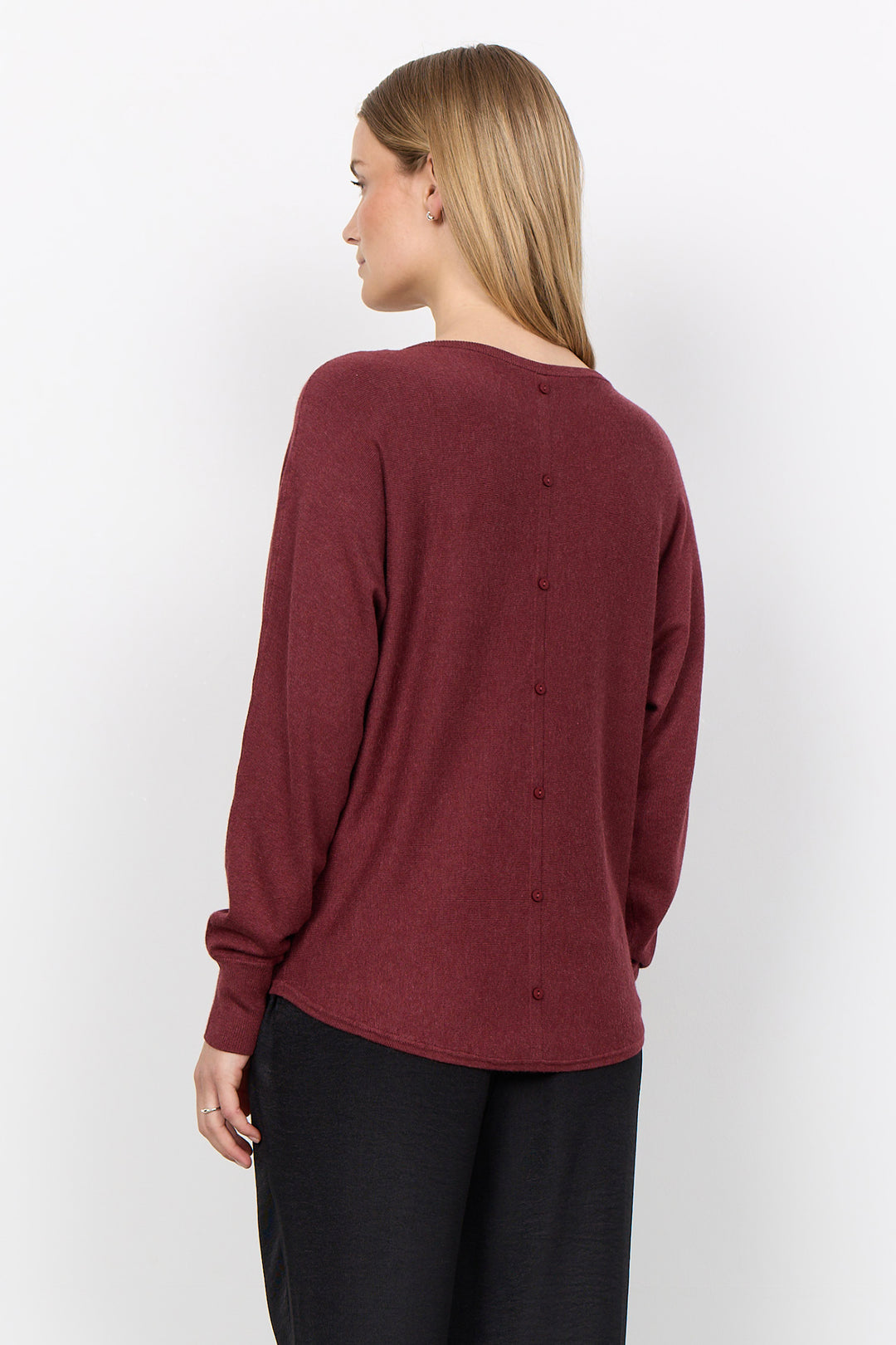 woman wearing a loose long sleeve sweater on a white background. 