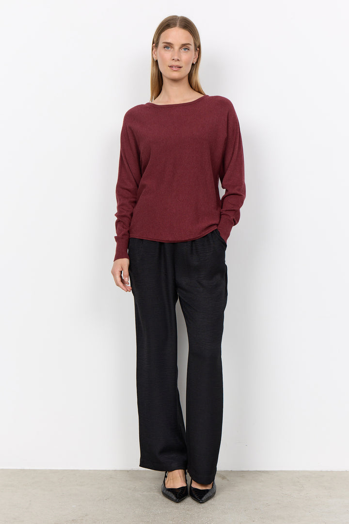 woman wearing a loose long sleeve sweater on a white background. 
