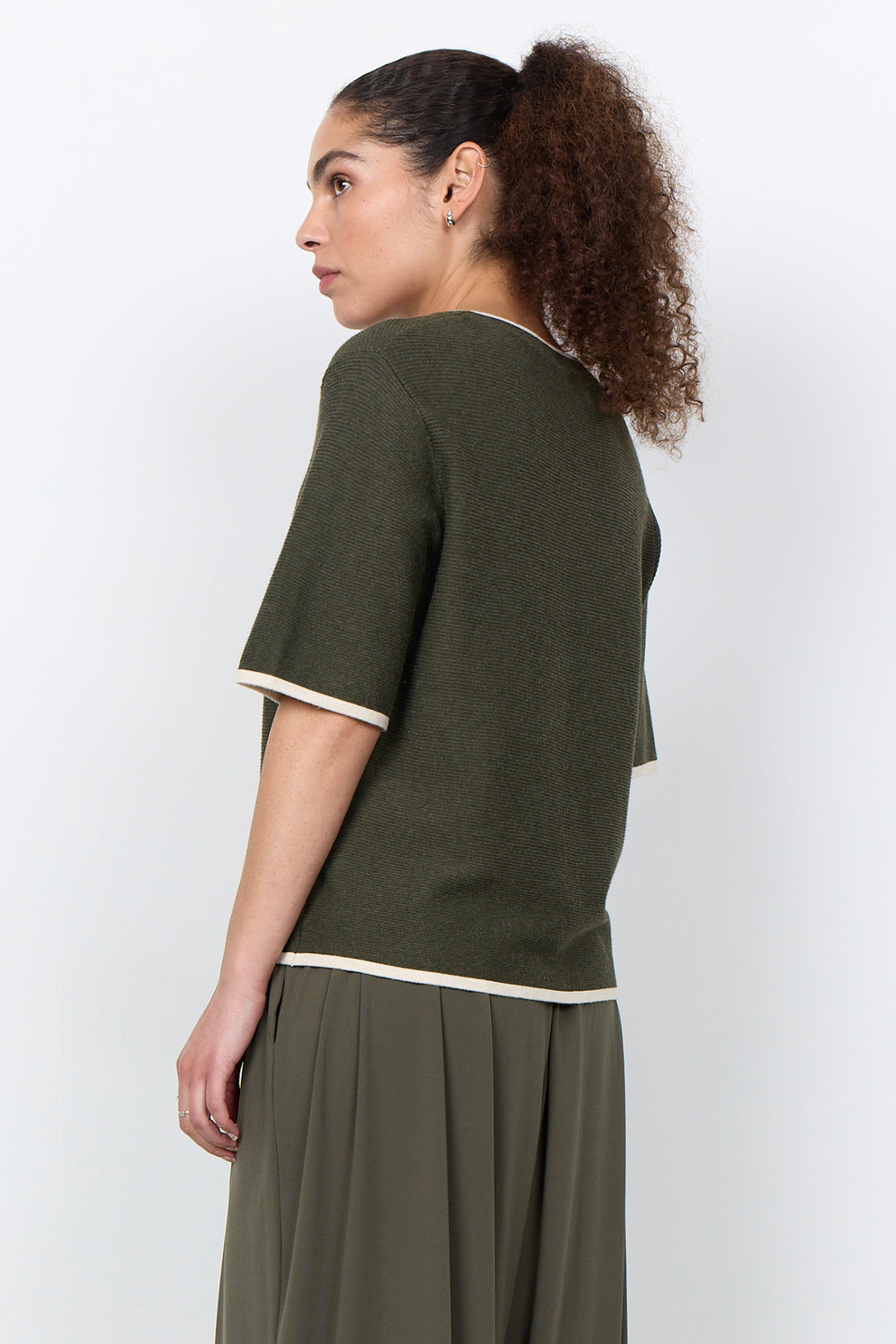 woman wearing a casual ribbed t-shirt sweater on a white background.