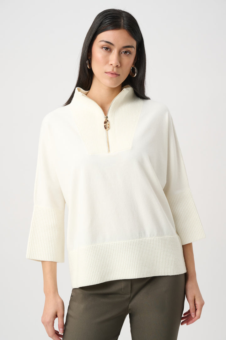 Woman wearing a cream-colored sweater with a zipper on a white background