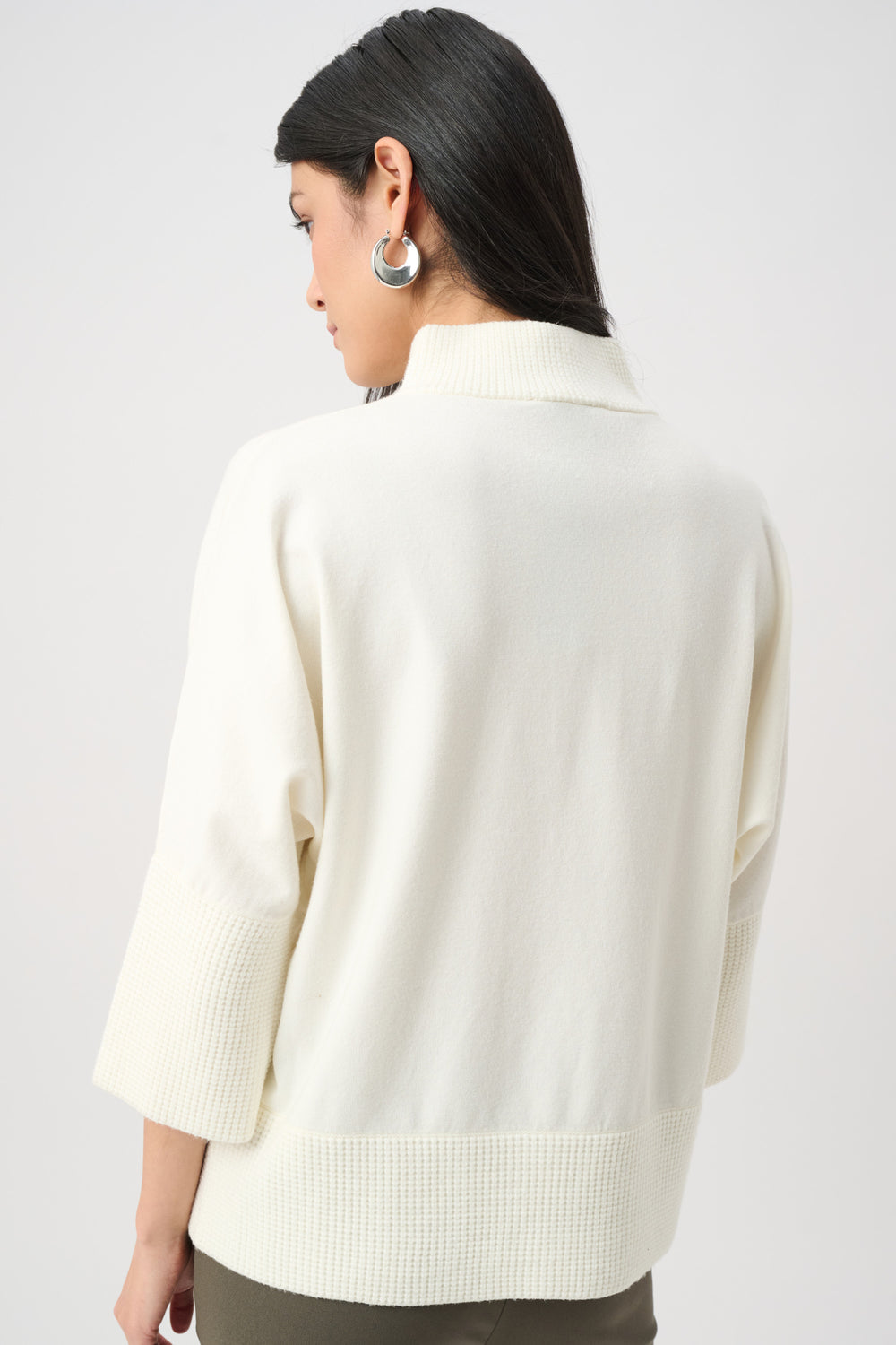 Person wearing a cream-colored sweater on a plain background