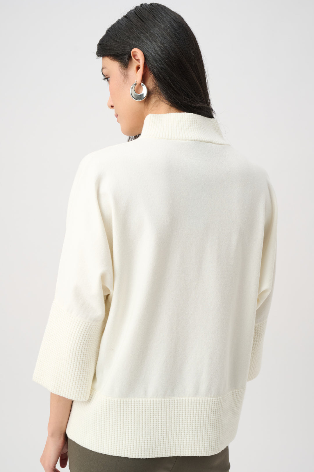 Person wearing a cream-colored sweater on a plain background