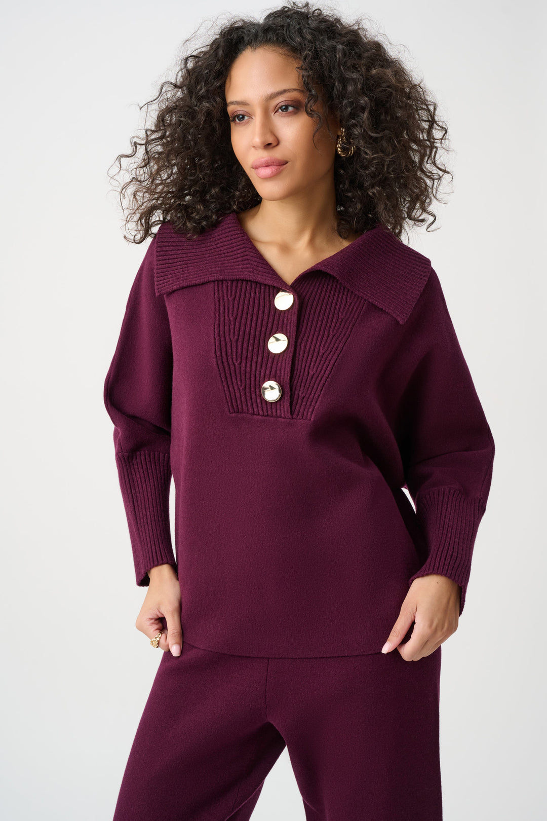 Woman wearing a burgundy outfit with a buttoned collar on a white background