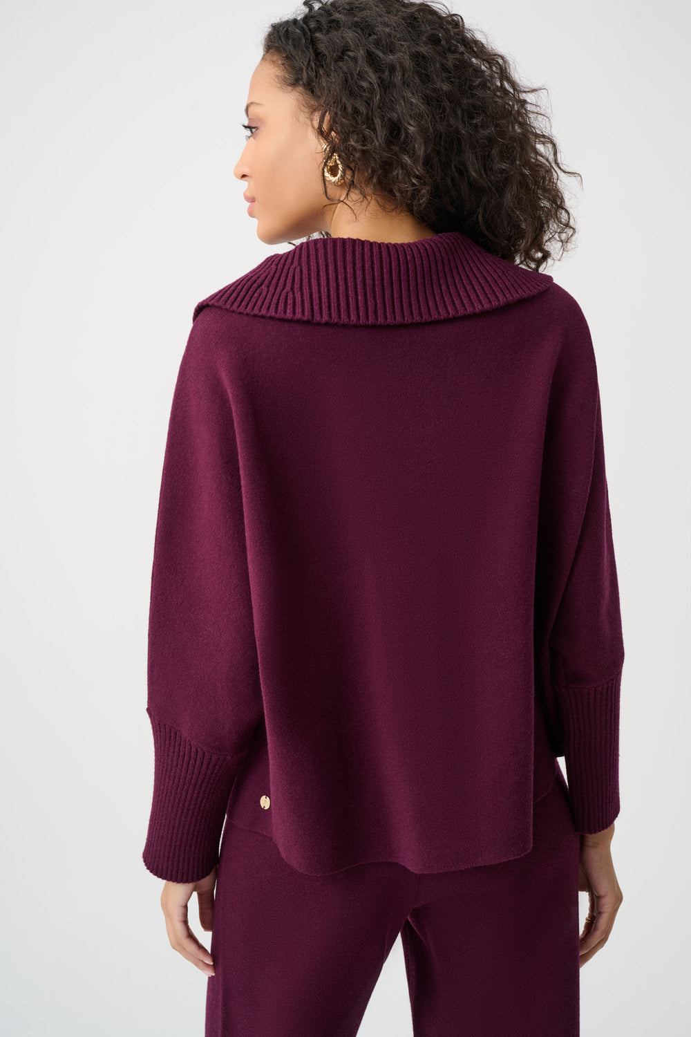 Person wearing a burgundy sweater and pants on a white background