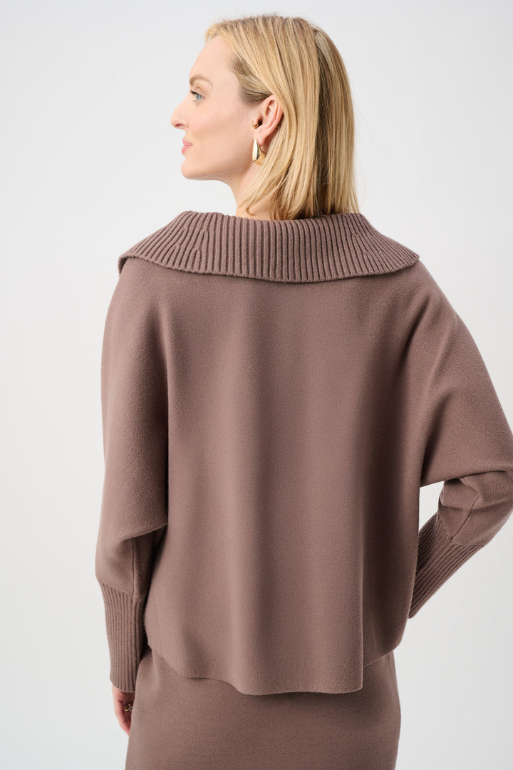 Woman wearing a brown sweater with a high collar on a white background