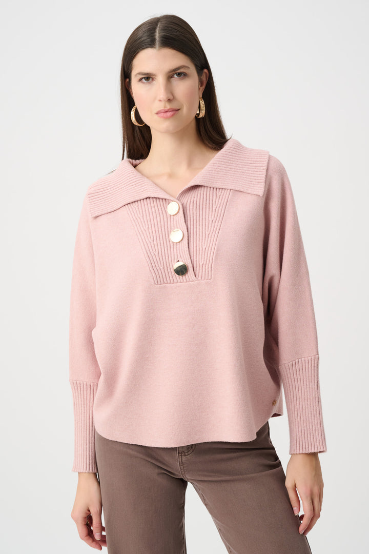 Woman wearing a pink sweater with a buttoned neckline on a white background