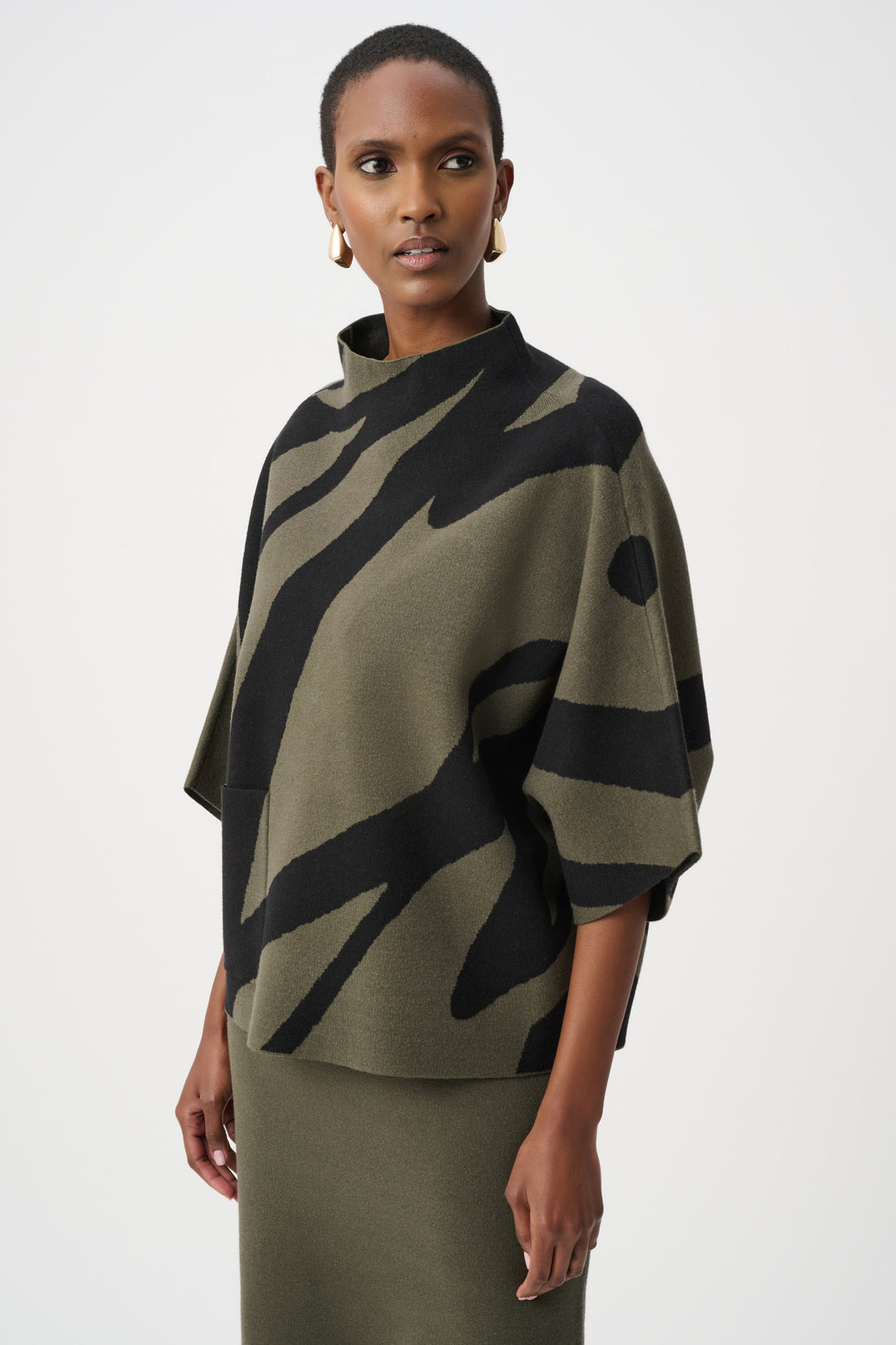 Woman wearing a green and black patterned poncho against a white background