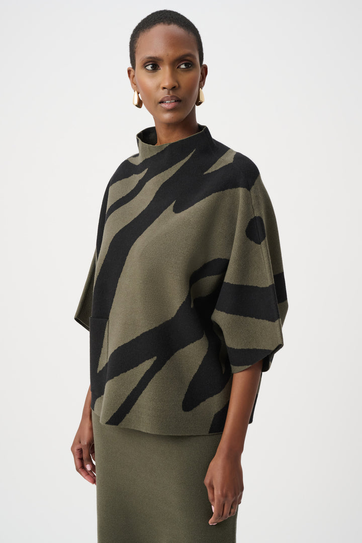 Woman wearing a green and black patterned poncho against a white background