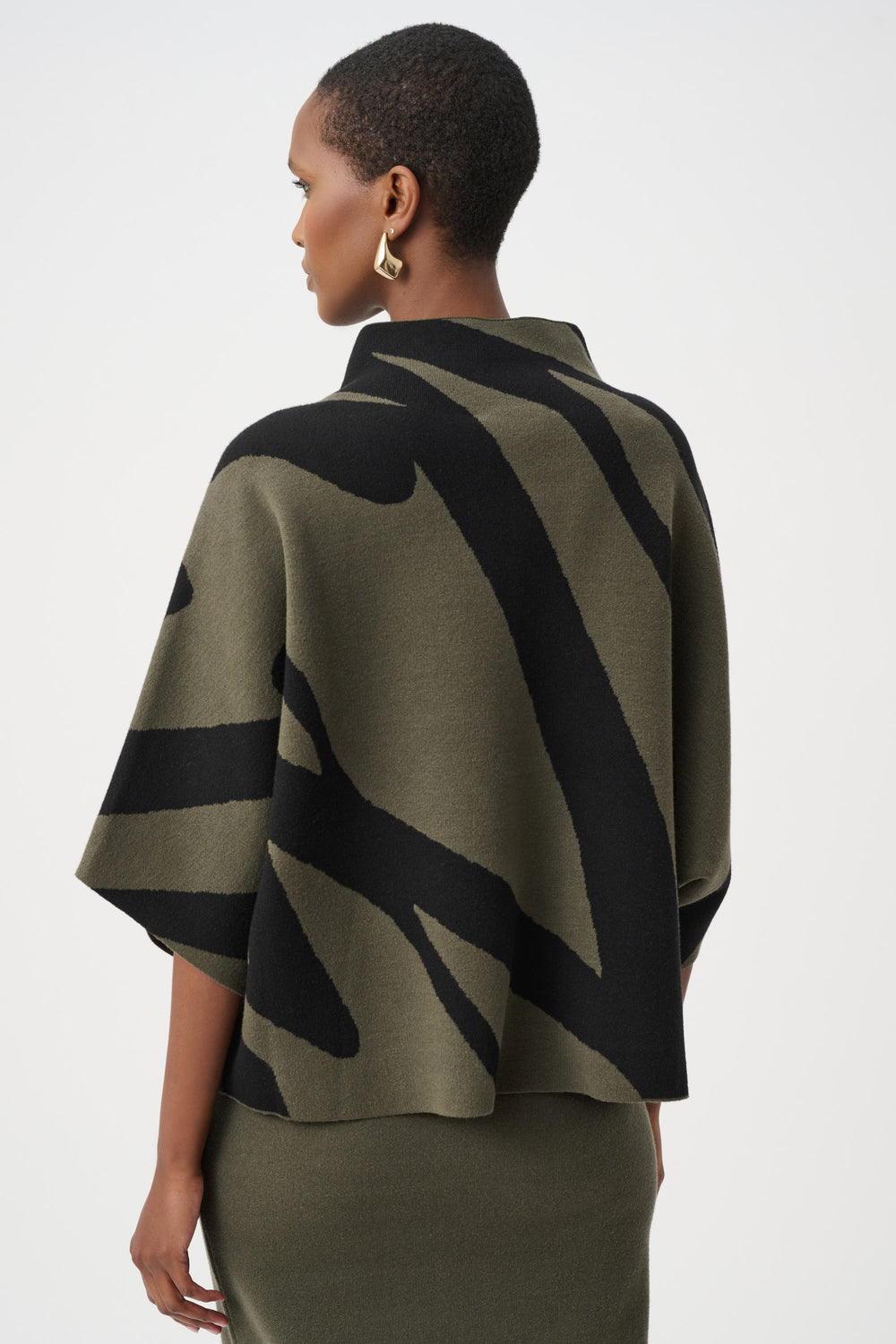 Woman wearing a green and black patterned cape on a white background