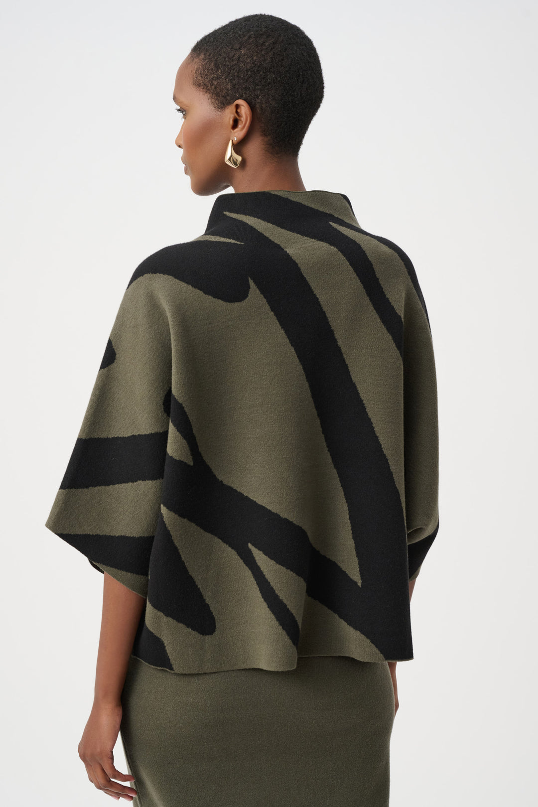 Woman wearing a green and black patterned cape on a white background