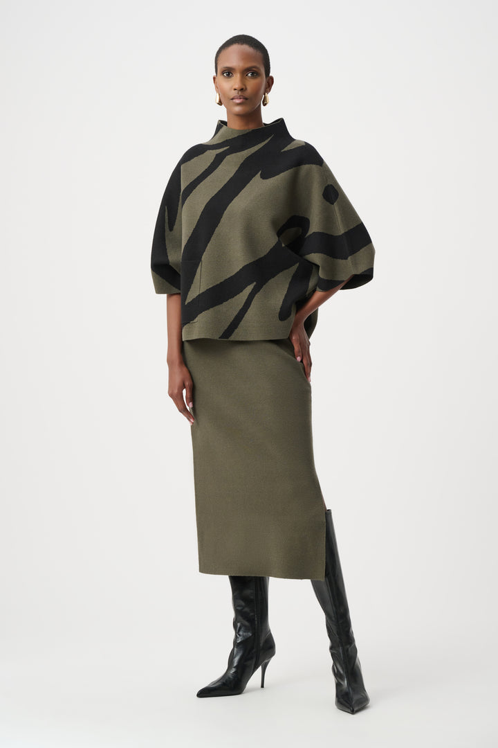 Woman wearing a green and black patterned poncho with a plain background