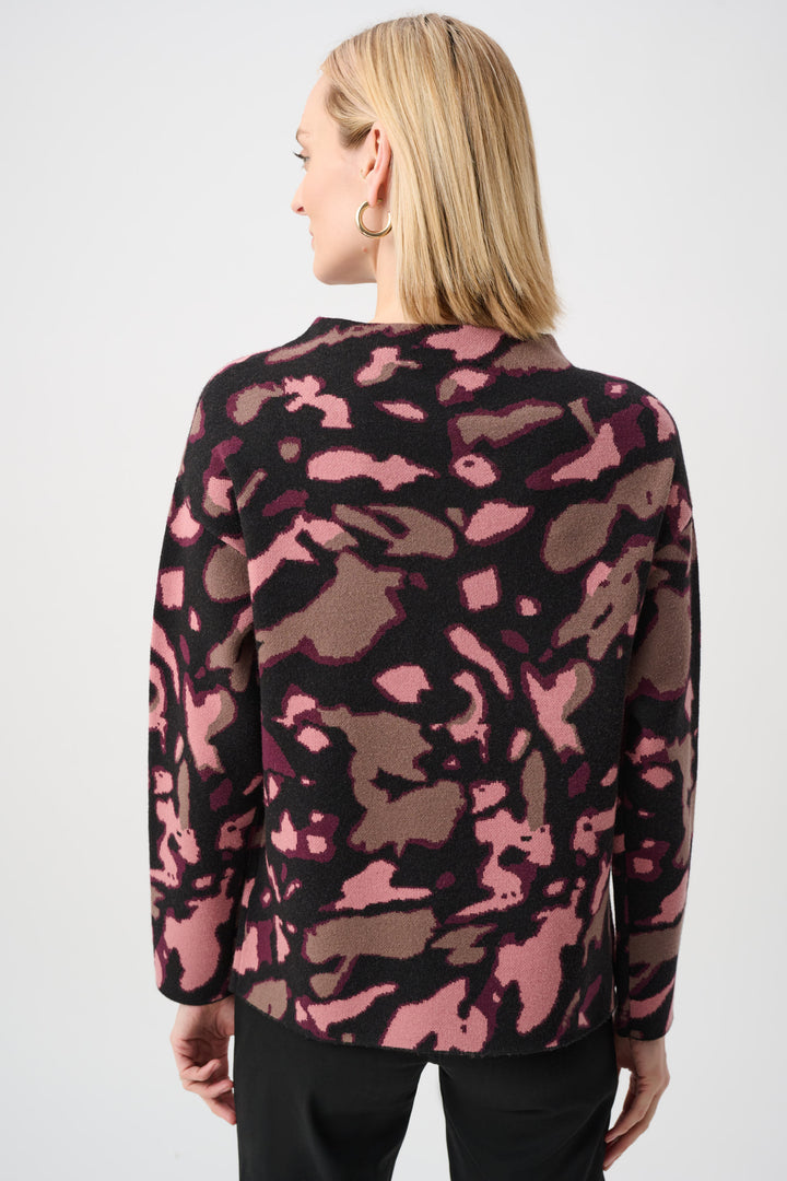 Person wearing a pink and black camouflage-patterned cardigan on a white background