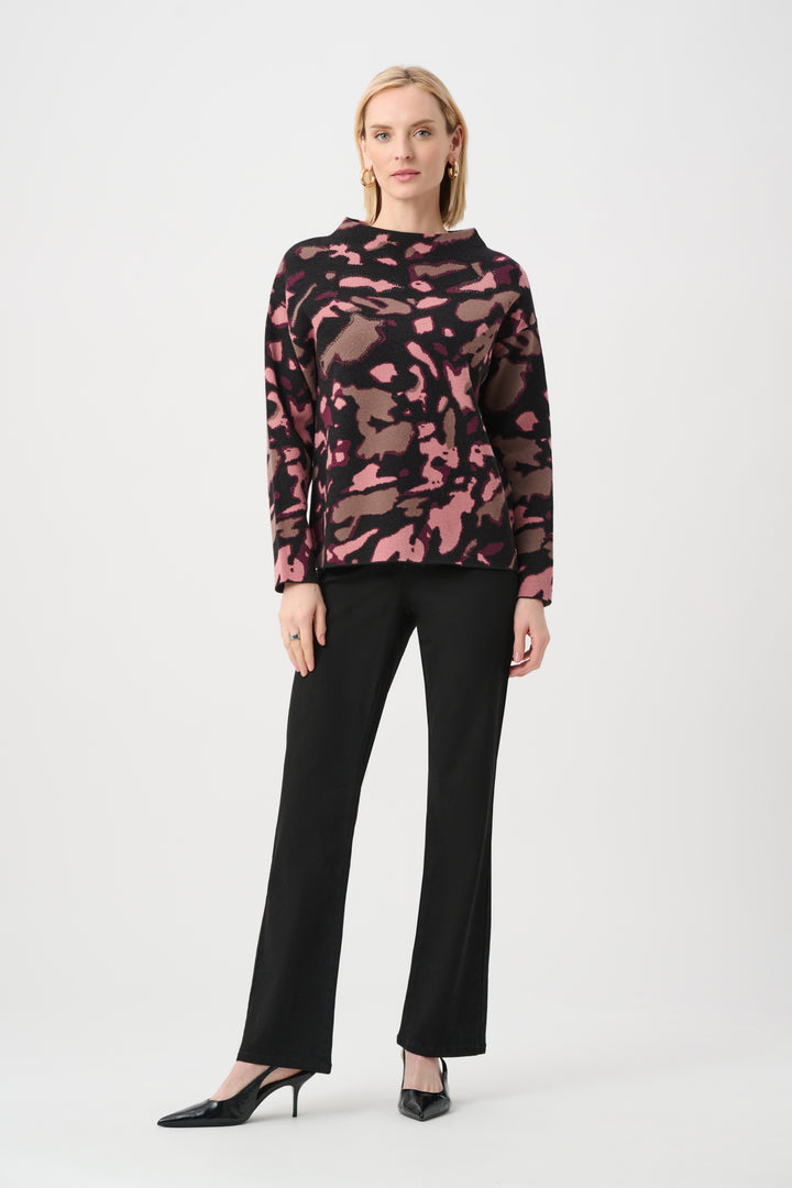 Woman wearing a pink and black patterned top with black pants on a white background