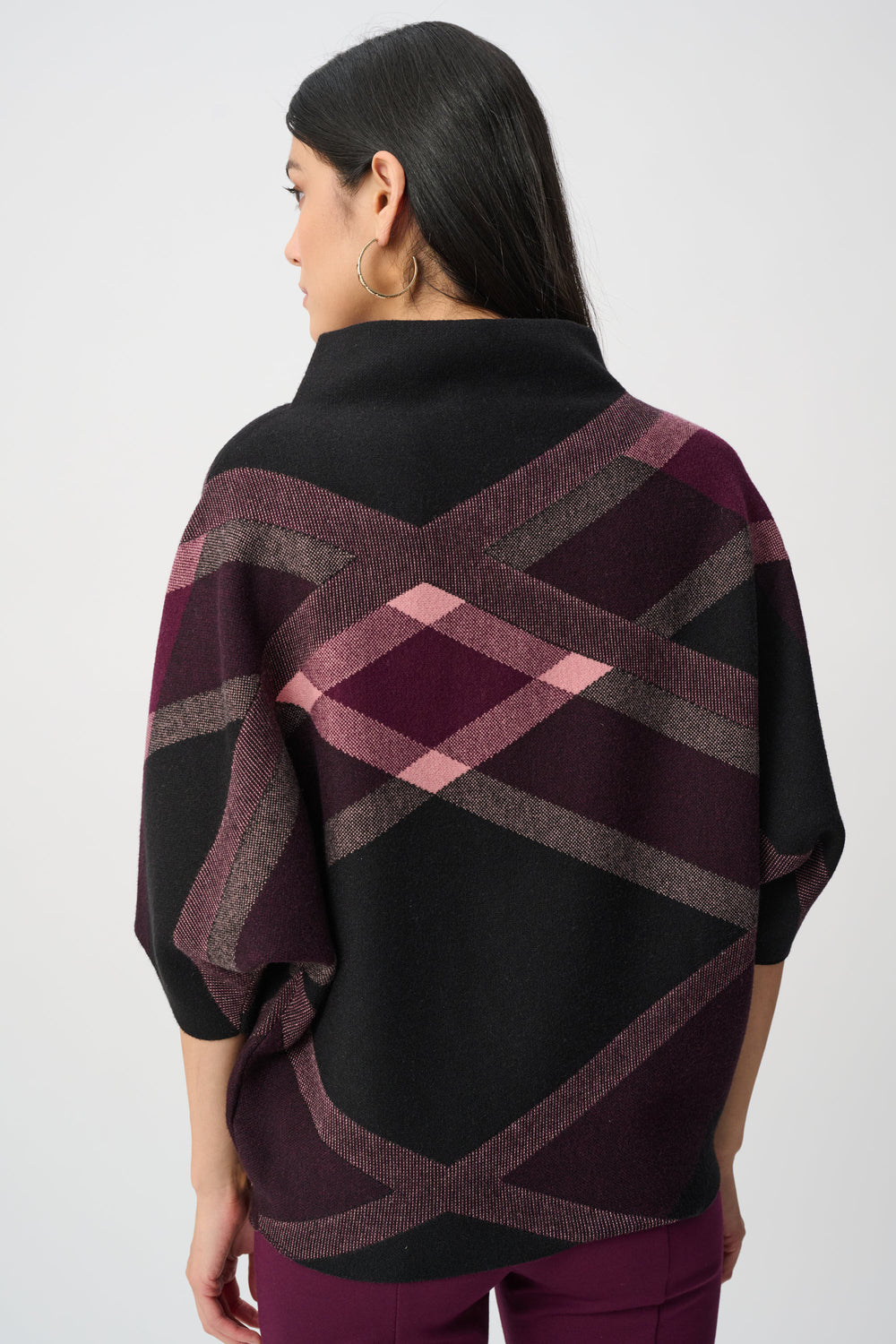 Woman wearing a black and plaid patterned poncho on a white background