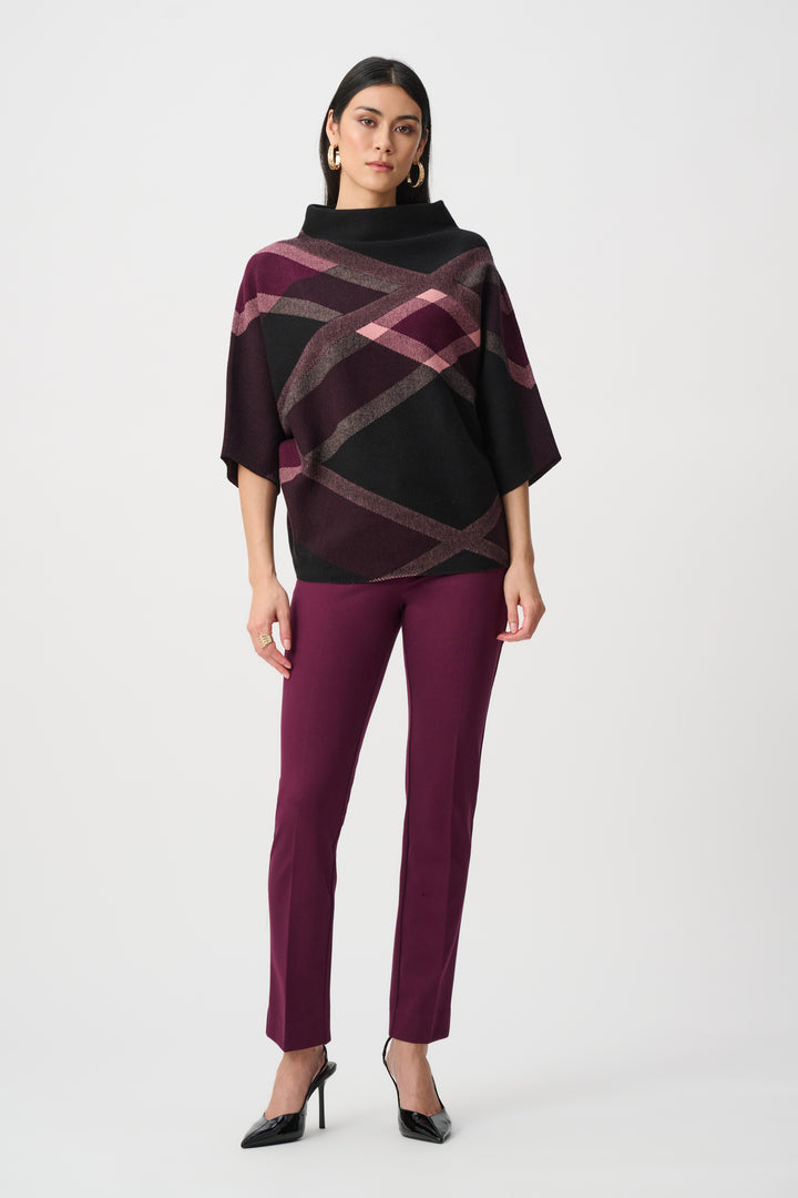 Woman wearing a black and purple patterned poncho with matching pants on a white background