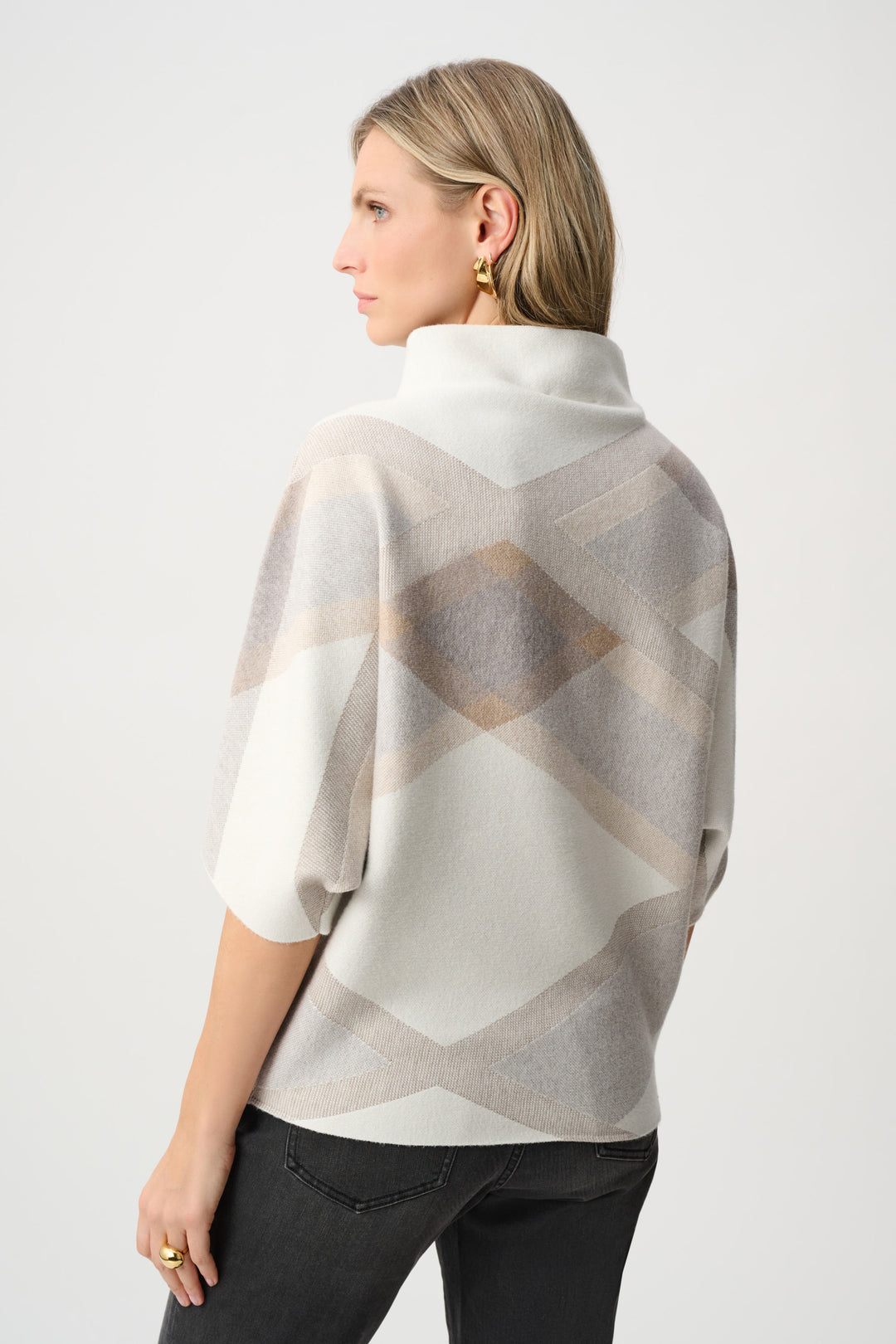 Woman wearing a patterned poncho against a white background