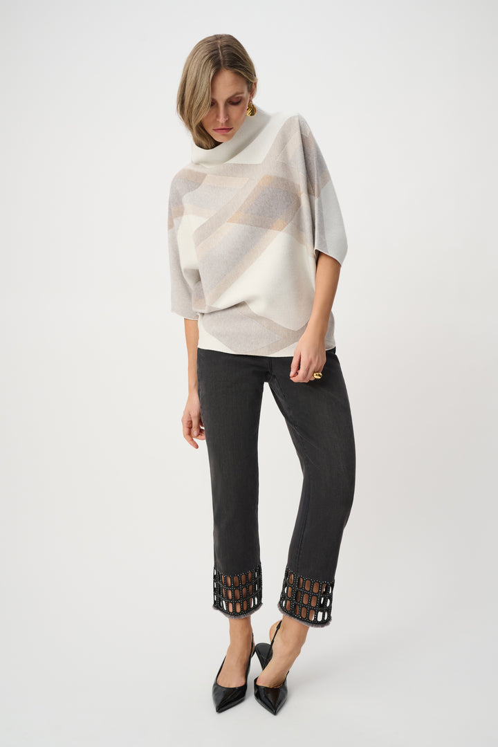 Woman wearing a patterned poncho and black pants with cut-out details on a white background