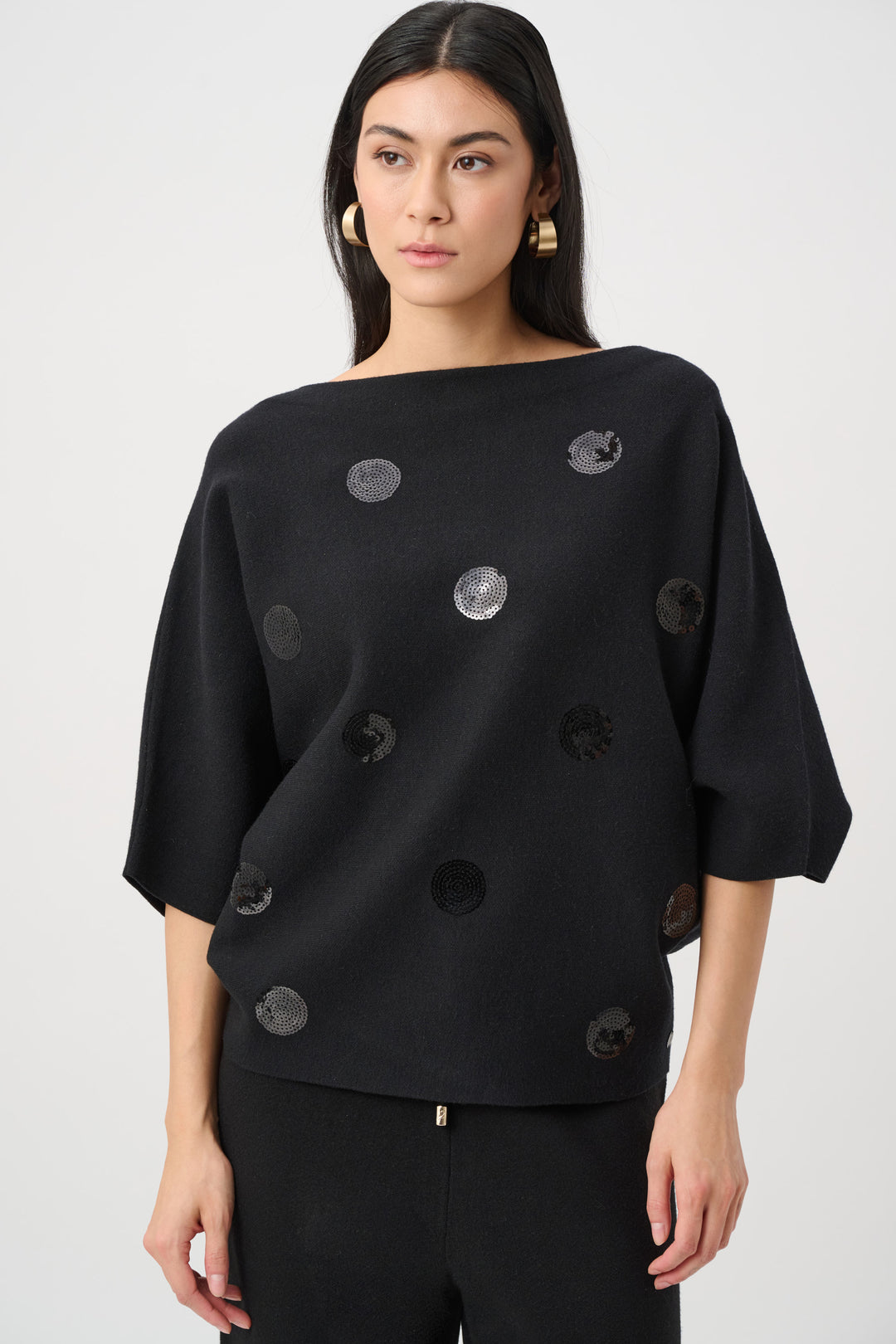 Woman wearing a black top with circular patterns on a white background